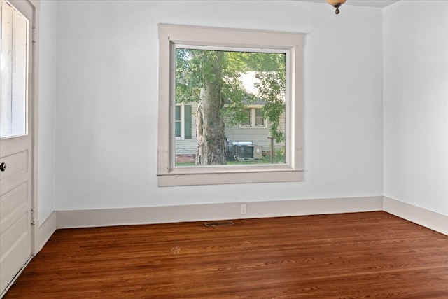 empty room featuring a wealth of natural light and dark wood-type flooring