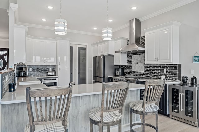 kitchen with wall chimney range hood, decorative backsplash, kitchen peninsula, and light hardwood / wood-style floors