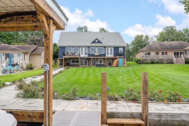 back of property with a deck, a patio, and a lawn