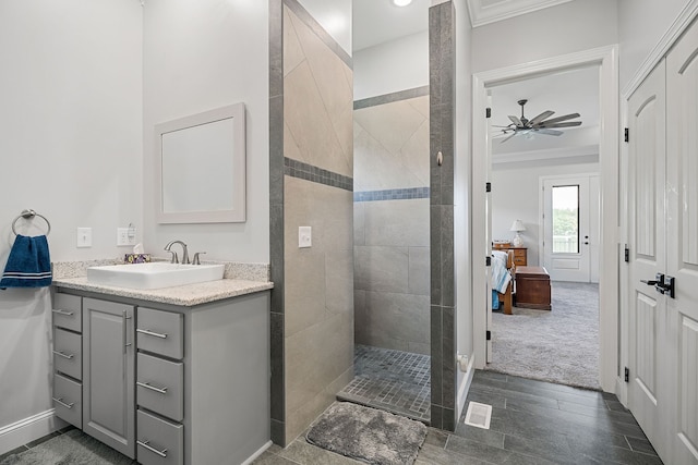 bathroom with vanity, tile patterned floors, ceiling fan, crown molding, and a tile shower