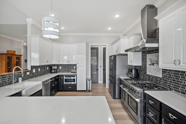 kitchen featuring white cabinetry, light wood-type flooring, backsplash, stainless steel appliances, and wall chimney exhaust hood