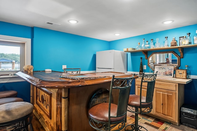 bar with white refrigerator and butcher block counters