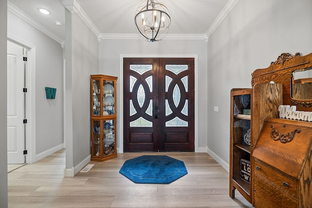 foyer entrance with a chandelier, ornamental molding, french doors, and light hardwood / wood-style floors