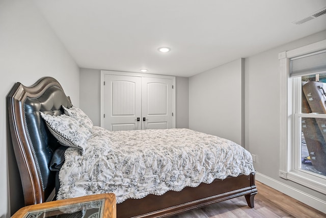 bedroom featuring a closet, multiple windows, and hardwood / wood-style floors