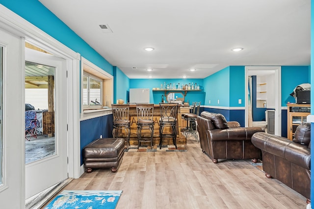 living room with light hardwood / wood-style floors and bar area