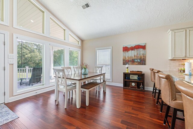 dining space with vaulted ceiling, hardwood / wood-style floors, and a textured ceiling