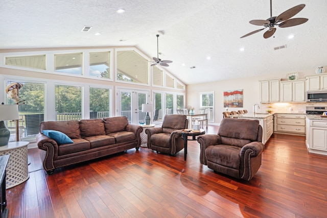 living room featuring hardwood / wood-style floors, sink, a textured ceiling, high vaulted ceiling, and ceiling fan