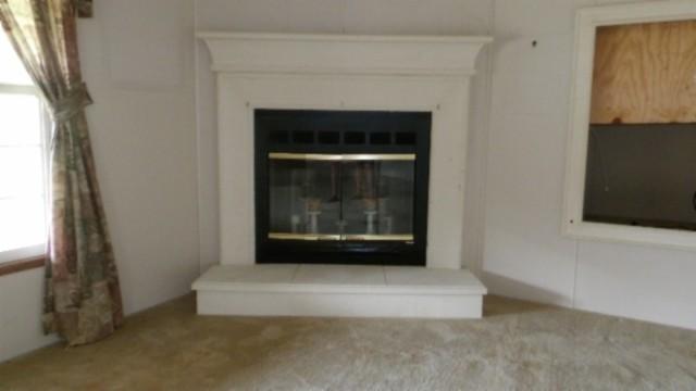 interior details featuring a tiled fireplace and carpet