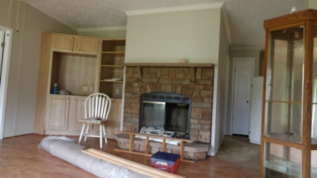 carpeted living room featuring a fireplace, a textured ceiling, crown molding, and lofted ceiling