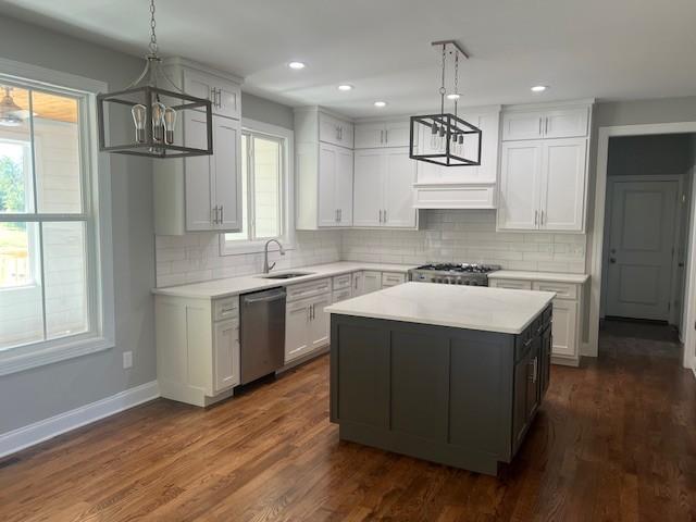 kitchen featuring pendant lighting, stainless steel dishwasher, a center island, and white cabinets