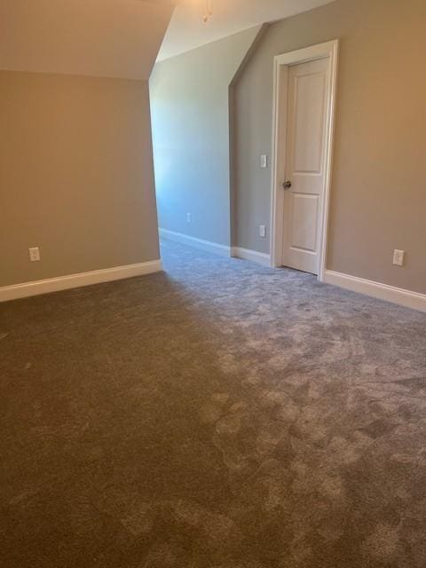 bonus room with lofted ceiling and dark carpet