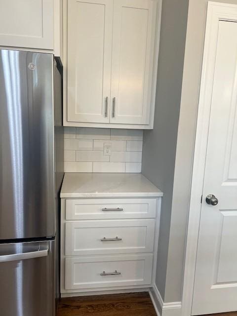 kitchen featuring white cabinetry, dark hardwood / wood-style floors, stainless steel fridge, and tasteful backsplash