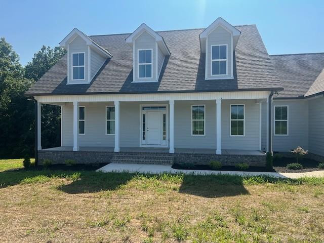 cape cod house with a porch and a front lawn