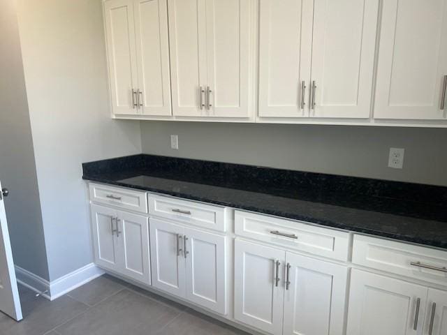 kitchen featuring light tile patterned flooring, white cabinets, and dark stone counters