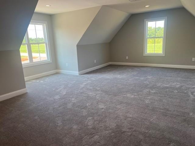 additional living space featuring lofted ceiling and dark carpet