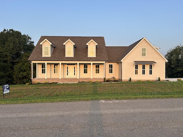 cape cod home featuring a front lawn and covered porch