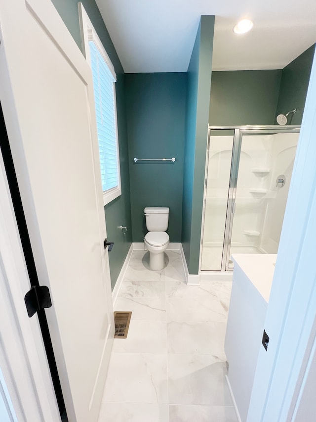 bathroom with a shower with shower door, vanity, tile patterned flooring, and toilet