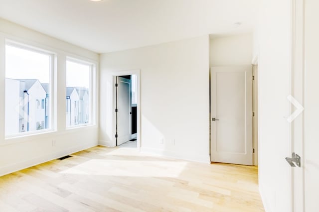 spare room with light wood-type flooring and a wealth of natural light