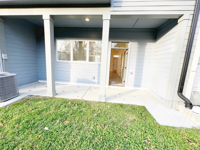 view of exterior entry featuring cooling unit and a yard