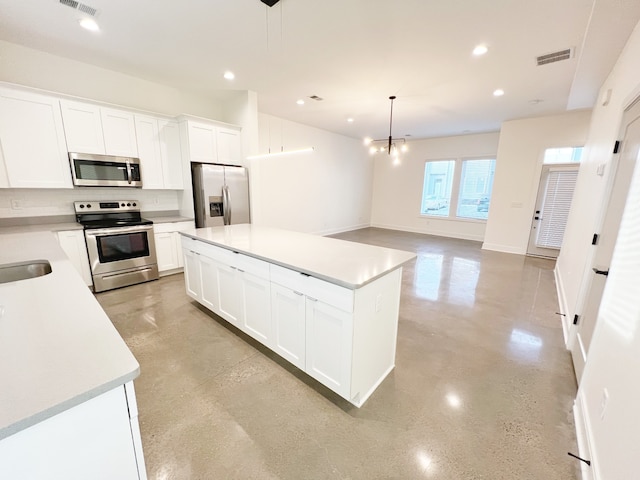 kitchen with white cabinets, a center island, stainless steel appliances, decorative backsplash, and decorative light fixtures