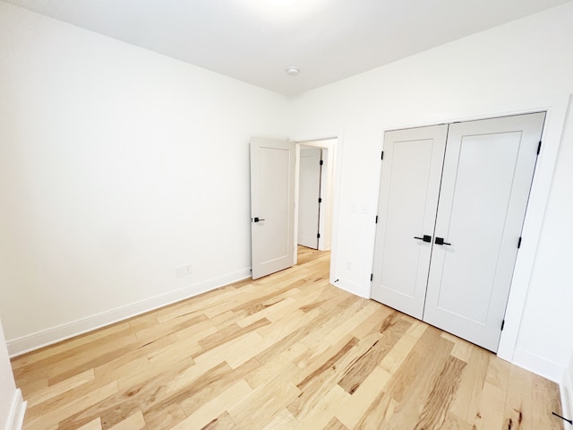 unfurnished bedroom featuring light hardwood / wood-style flooring and a closet