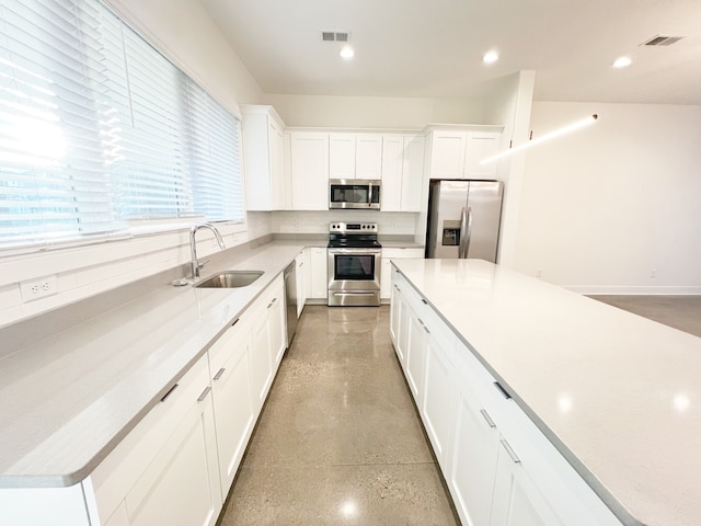 kitchen featuring appliances with stainless steel finishes, tasteful backsplash, white cabinets, and sink