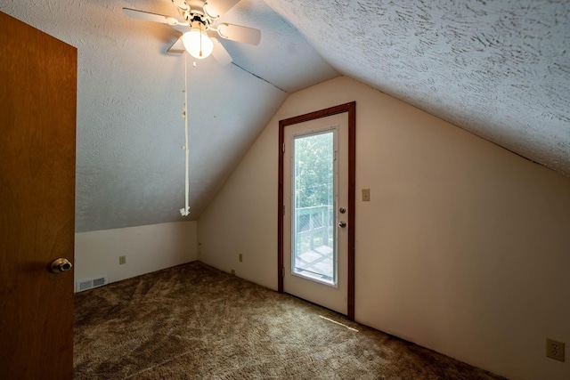 additional living space featuring lofted ceiling, visible vents, carpet flooring, ceiling fan, and a textured ceiling