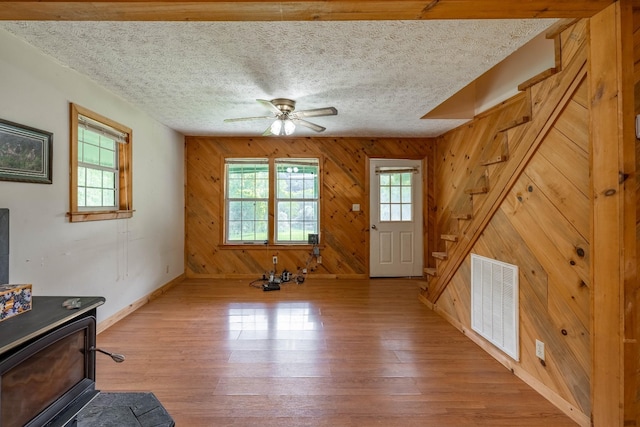 interior space with a textured ceiling, wood finished floors, visible vents, and baseboards