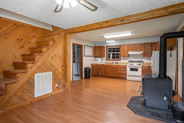 kitchen with visible vents, electric range, a wood stove, wood walls, and light wood-type flooring