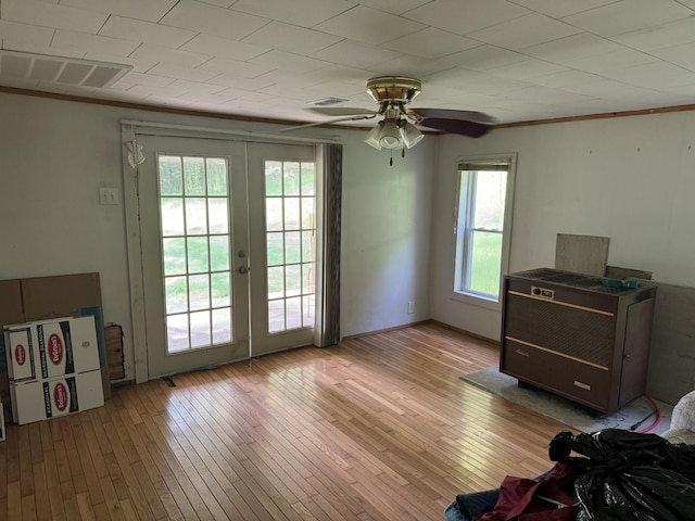 doorway with french doors, ornamental molding, light wood-type flooring, and visible vents