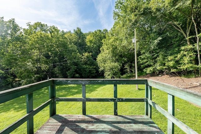 wooden terrace with a view of trees and a lawn