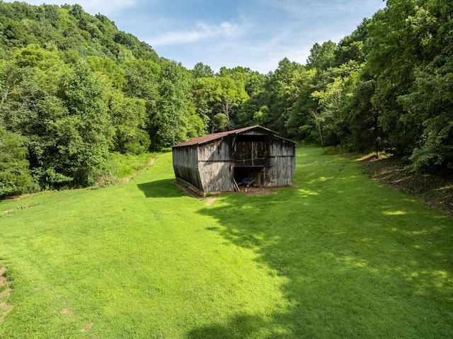 view of yard featuring an outbuilding and a view of trees