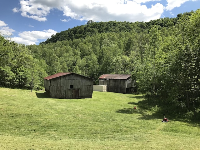 view of yard with an outbuilding, a pole building, and a wooded view