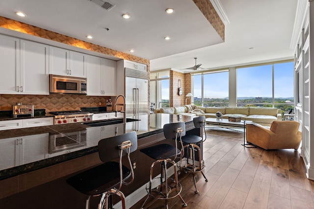 kitchen featuring built in appliances, sink, decorative backsplash, and plenty of natural light