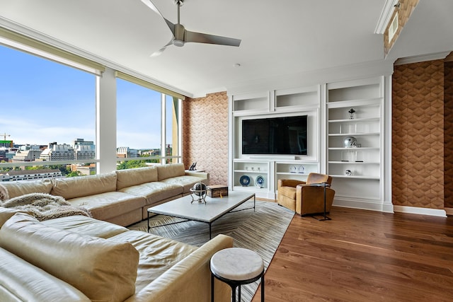 living room featuring built in shelves, crown molding, hardwood / wood-style floors, and ceiling fan