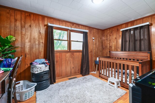 bedroom with light hardwood / wood-style floors and wooden walls