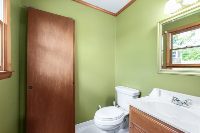 half bathroom with toilet, baseboards, vanity, and crown molding