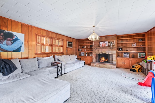 living room featuring carpet floors, built in features, a fireplace, an AC wall unit, and wood walls