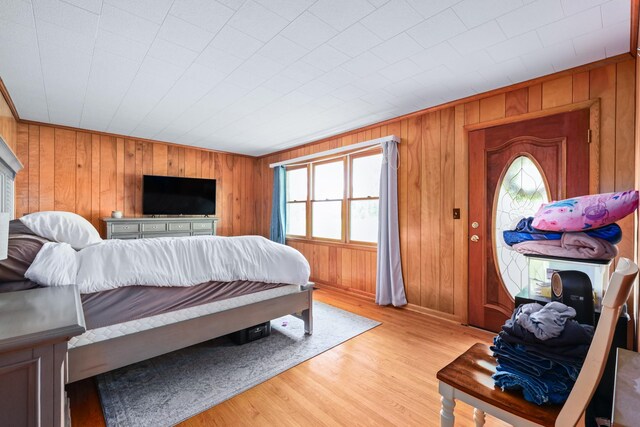 bedroom featuring light wood-type flooring and wooden walls