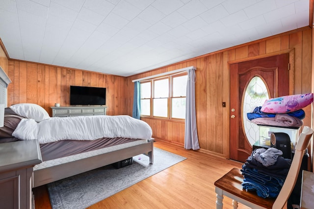 bedroom featuring wooden walls and light wood-style flooring