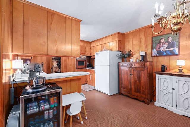 kitchen featuring light carpet, brown cabinets, oven, a peninsula, and freestanding refrigerator