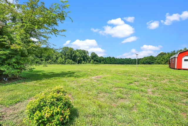 view of yard featuring a storage unit, a rural view, and an outdoor structure