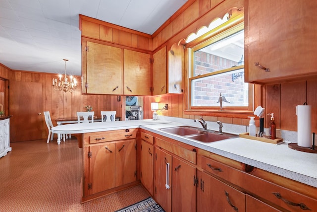 kitchen featuring light countertops, a sink, decorative light fixtures, and a peninsula