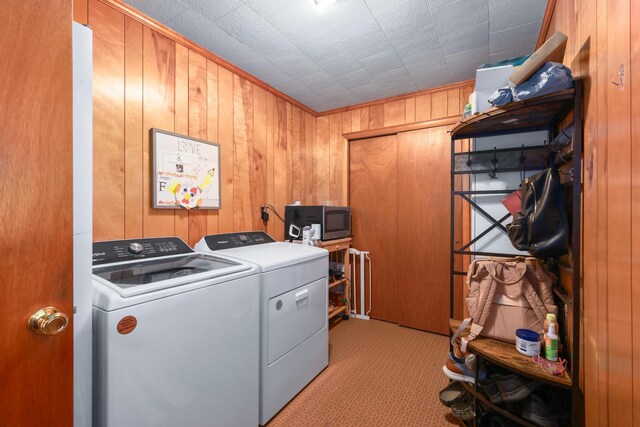 washroom featuring wood walls, light colored carpet, and washing machine and clothes dryer