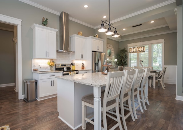 kitchen featuring dark wood-type flooring, white cabinets, stainless steel appliances, and wall chimney range hood