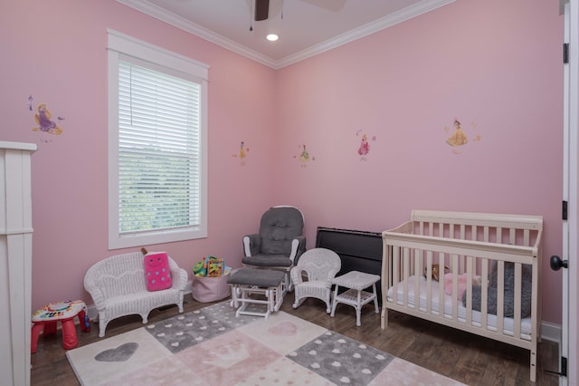 bedroom with hardwood / wood-style floors, a nursery area, ornamental molding, and ceiling fan