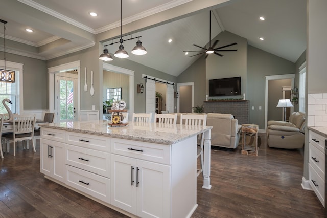 kitchen with white cabinets, a kitchen breakfast bar, a barn door, and decorative light fixtures