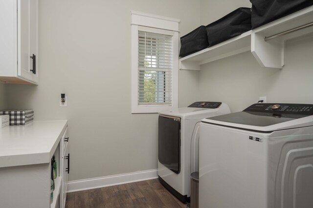 clothes washing area with washing machine and clothes dryer, cabinets, and dark hardwood / wood-style floors