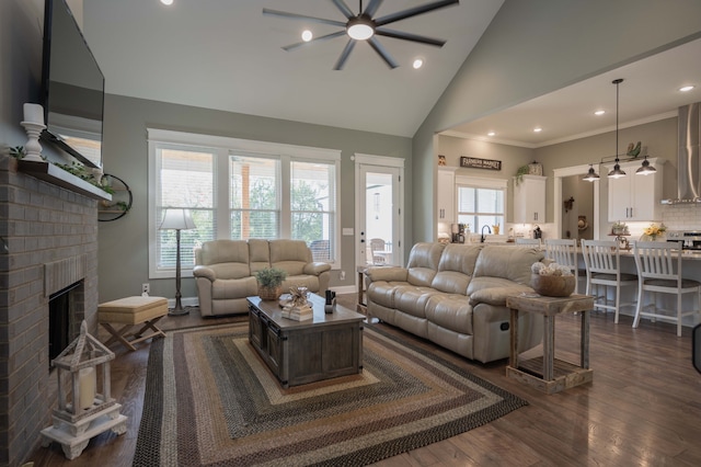 living room featuring ornamental molding, ceiling fan, high vaulted ceiling, a fireplace, and dark hardwood / wood-style floors