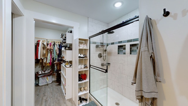 bathroom with a shower with shower door and hardwood / wood-style flooring